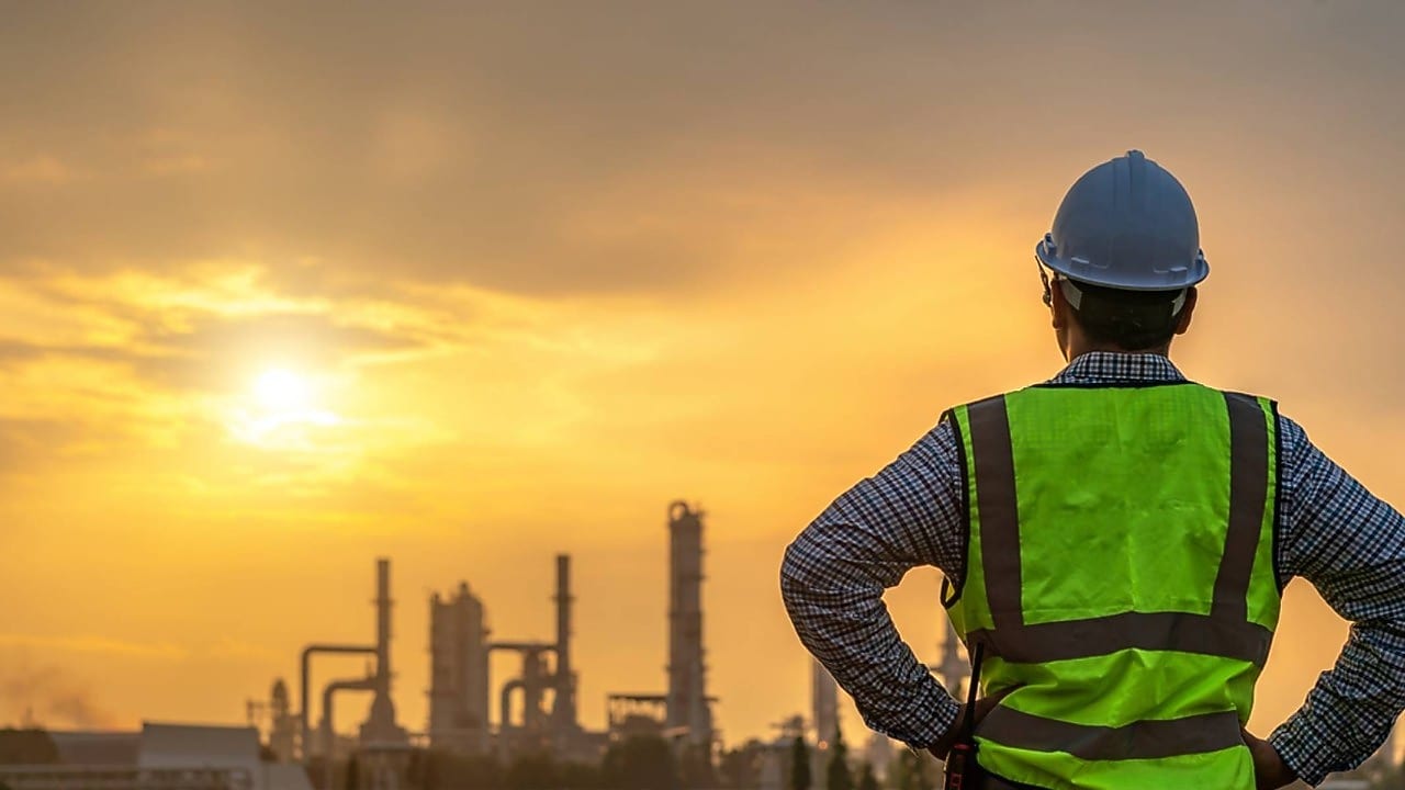 Worker looking over a refinery at dawn