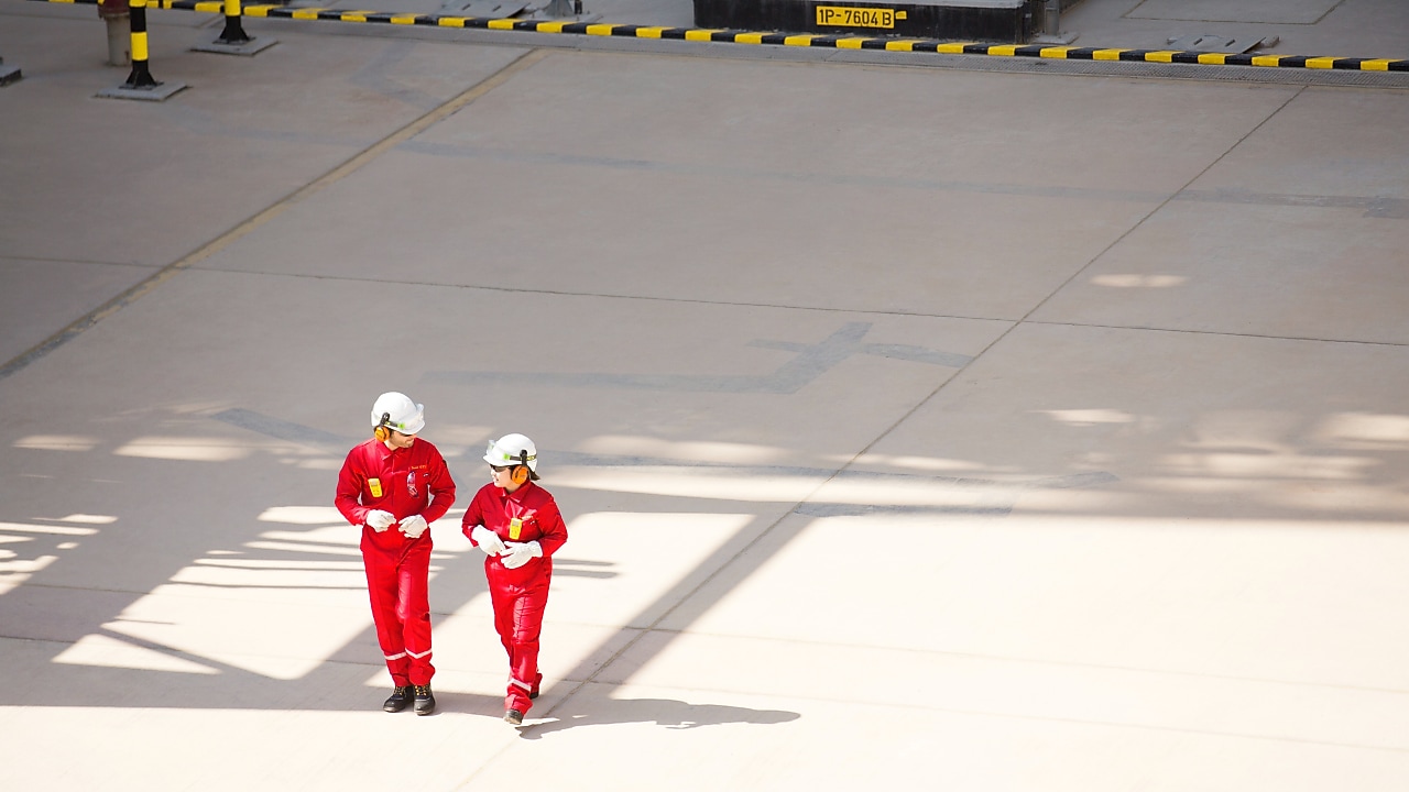 Two workers in red jumpsuits walking and talking