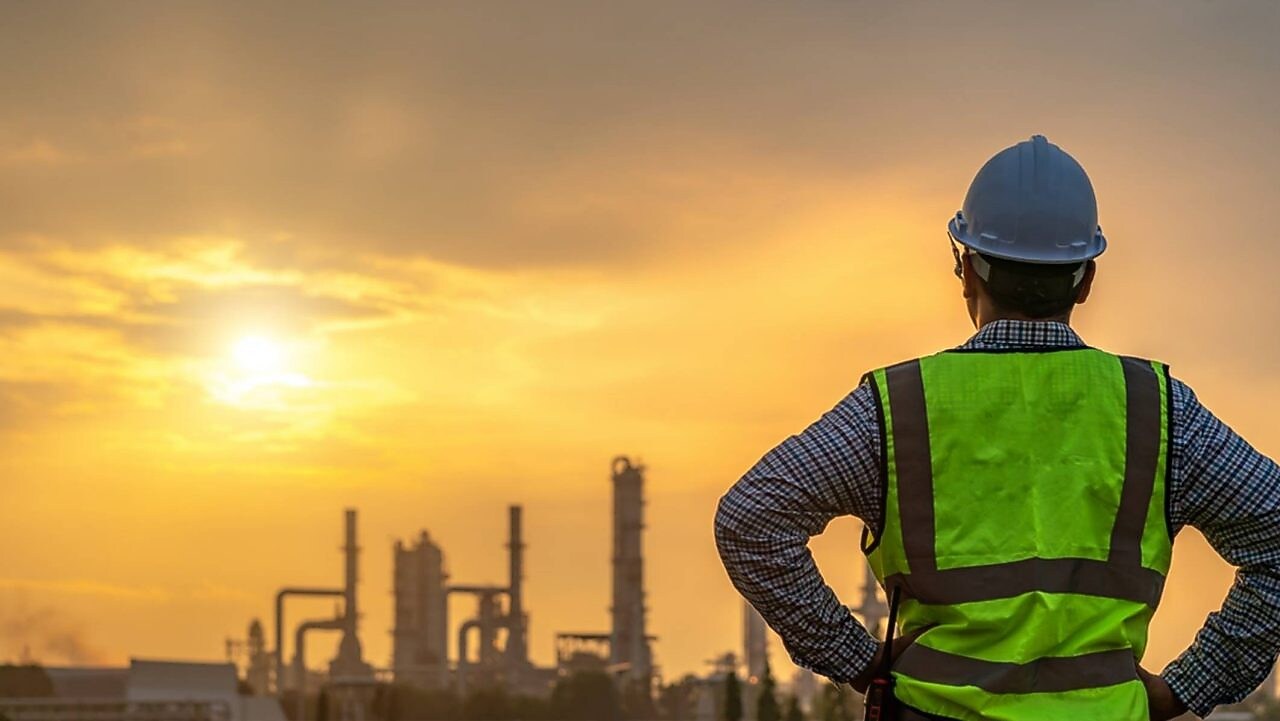 Worker looking over a refinery at dawn