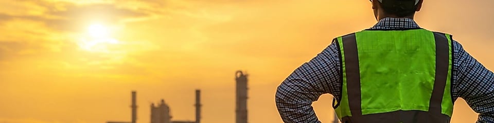 Worker looking over a refinery at dawn